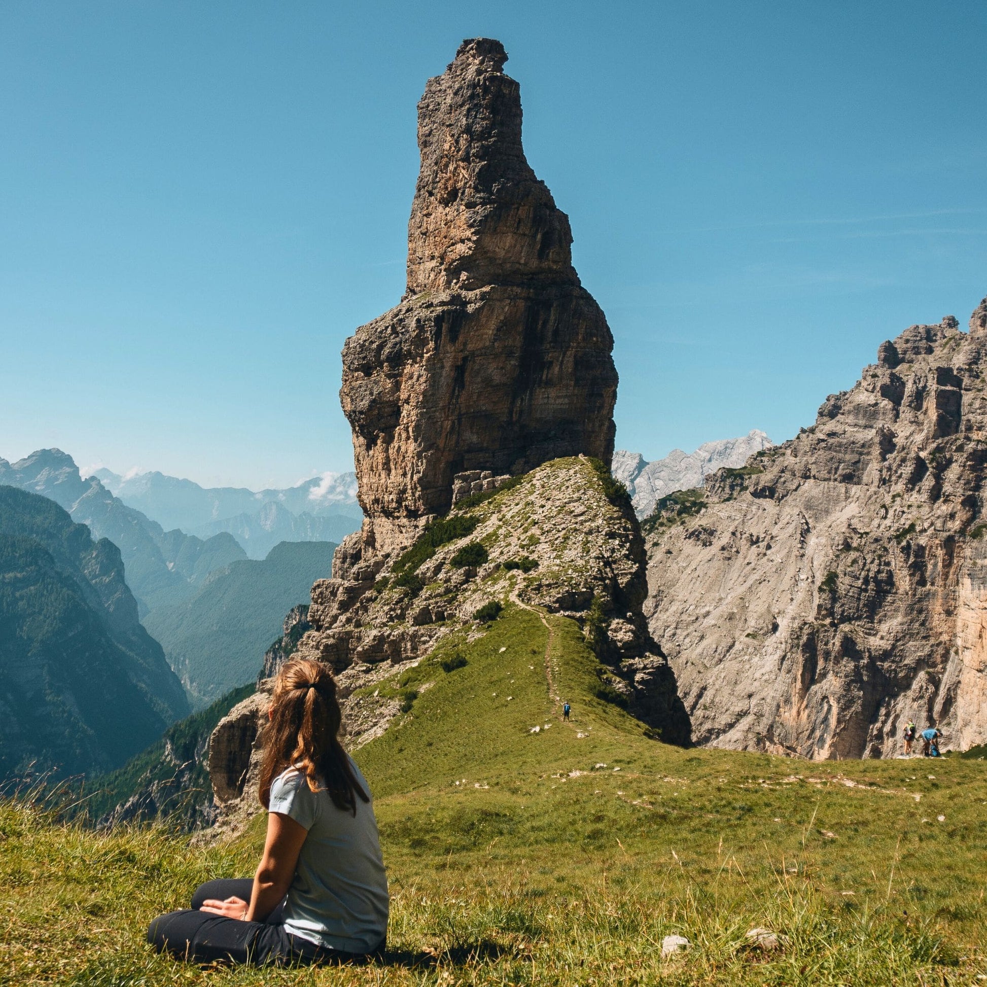 Solo hiker admiring Campanile di Val Montanaia limestone tower from alpine meadow in Friulian Dolomites UNESCO site