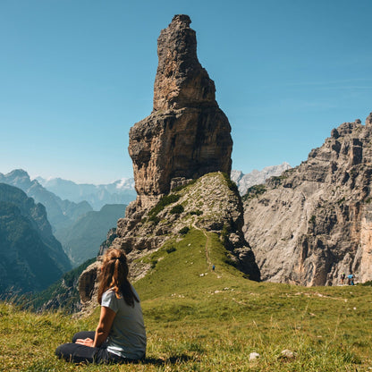 Solo hiker admiring Campanile di Val Montanaia limestone tower from alpine meadow in Friulian Dolomites UNESCO site