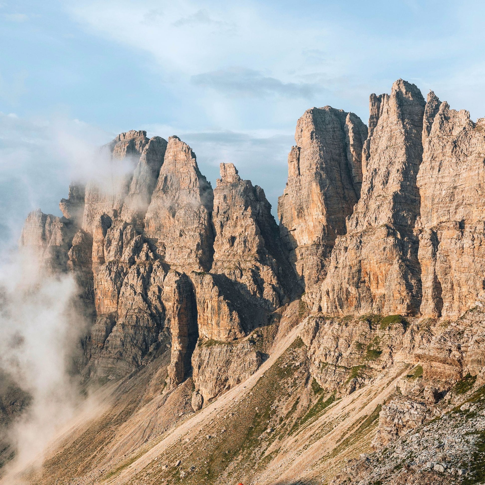 Golden sunrise illuminating limestone towers emerging from clouds in Friulian Dolomites UNESCO World Heritage area