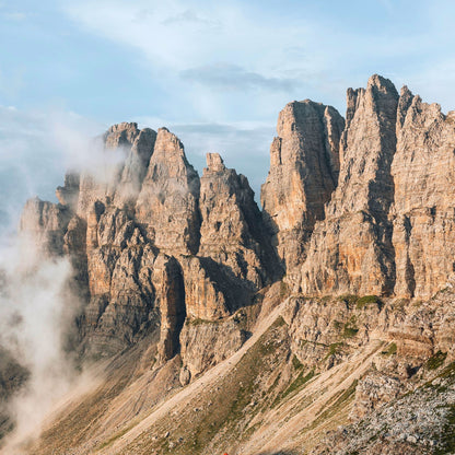 Golden sunrise illuminating limestone towers emerging from clouds in Friulian Dolomites UNESCO World Heritage area