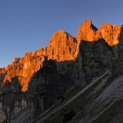 Orange alpenglow illuminating dramatic limestone peaks at sunset in Dolomiti Friulane UNESCO World Heritage site
