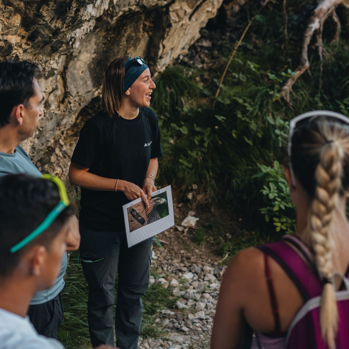 Professional mountain guide teaching hikers about local wildlife with photo guide during Friulian Dolomites wilderness trek