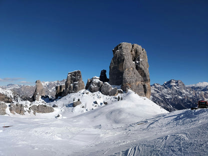 Le Cinque Torri innevate sopra le piste di Cortina d'Ampezzo, tappa del ski safari ski-in ski-out nelle Dolomiti
