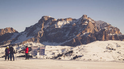 Sciatori davanti ai cartelli delle piste in Alta Badia, con il Sasso della Croce innevato