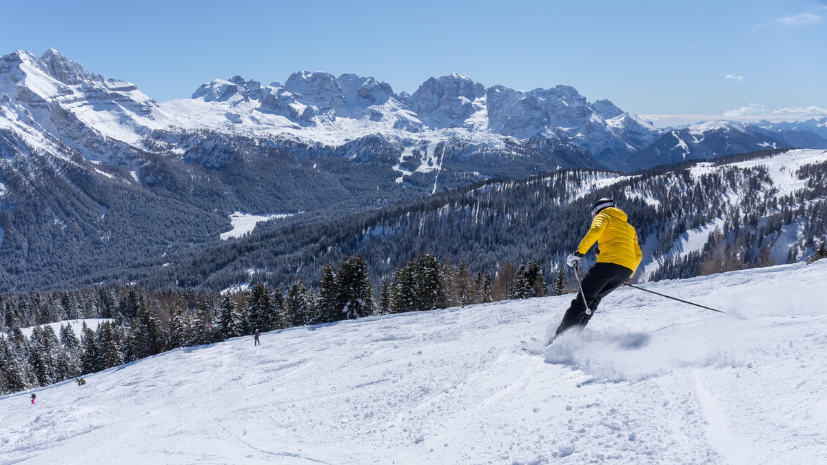 Sciatore sulle piste di Folgarida in Val di Sole con le Dolomiti di Brenta sullo sfondo